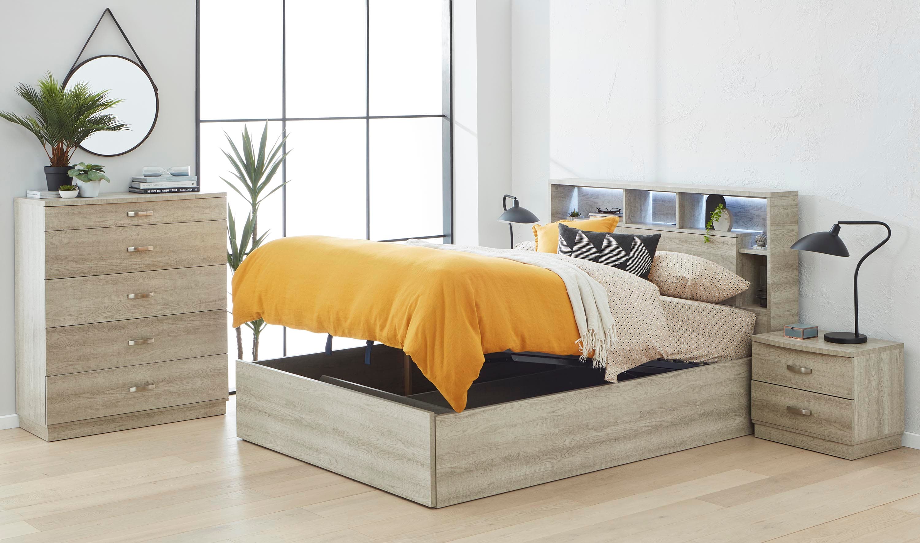 Timber-look gas lift storage bed with yellow quilt, bookcase headboard, bedside table and tallboy