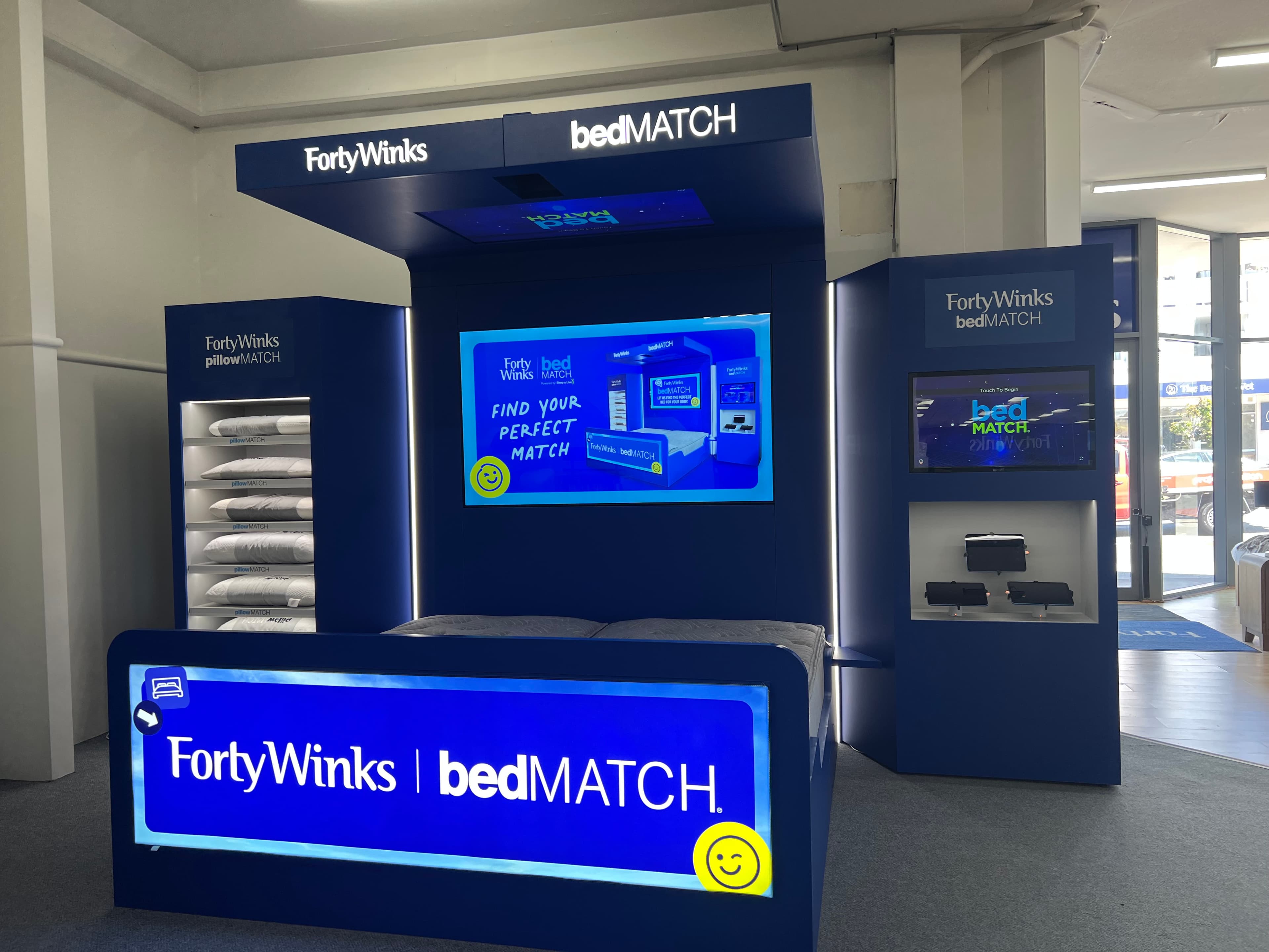 Customer lying on a bedMATCH® fitting bed while a team member looks on.