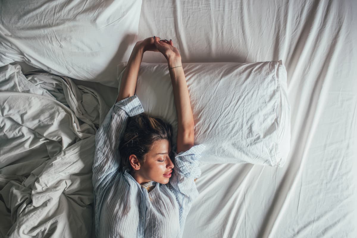 Woman stretching in bed after a good night's sleep.