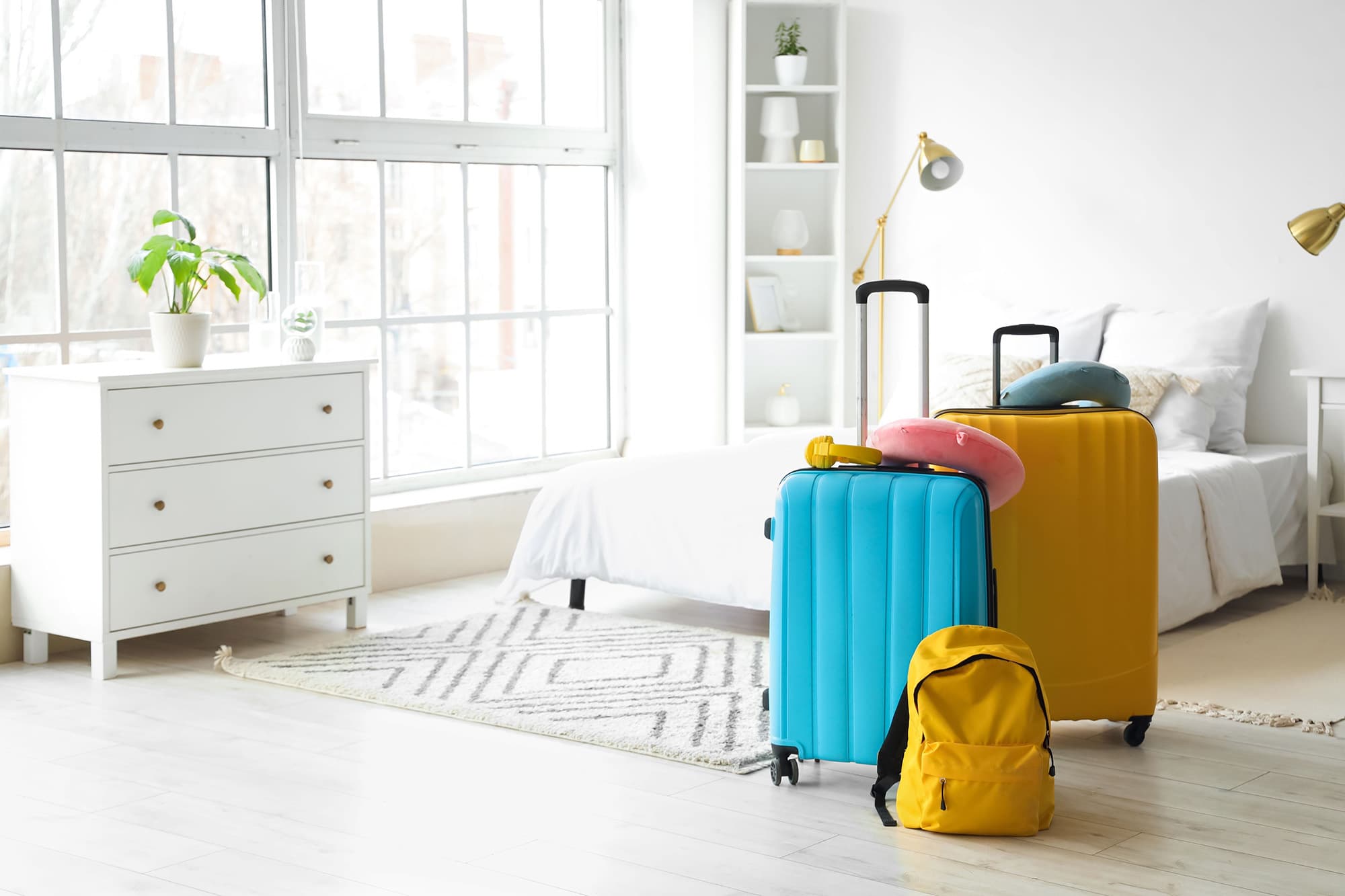Bright guest bedroom with suitcases waiting by the bed.