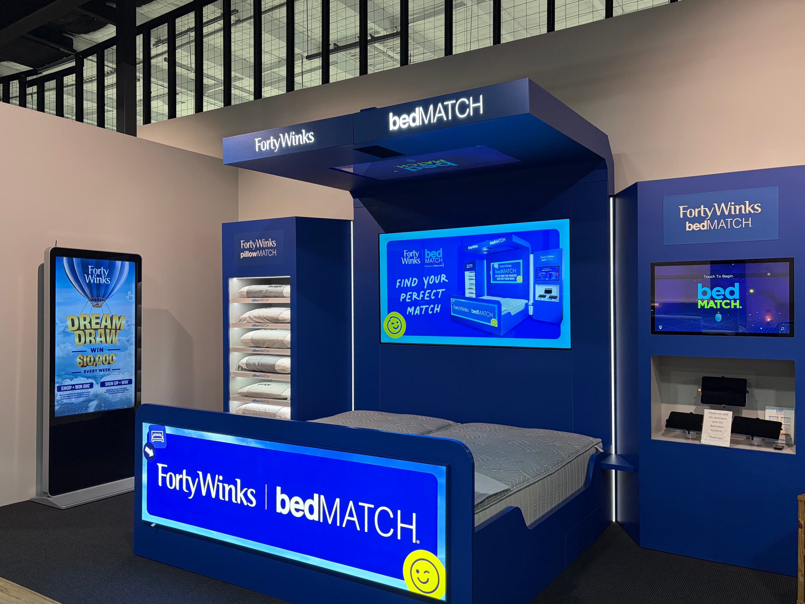 Customer lying on a bedMATCH® fitting bed while a team member looks on.