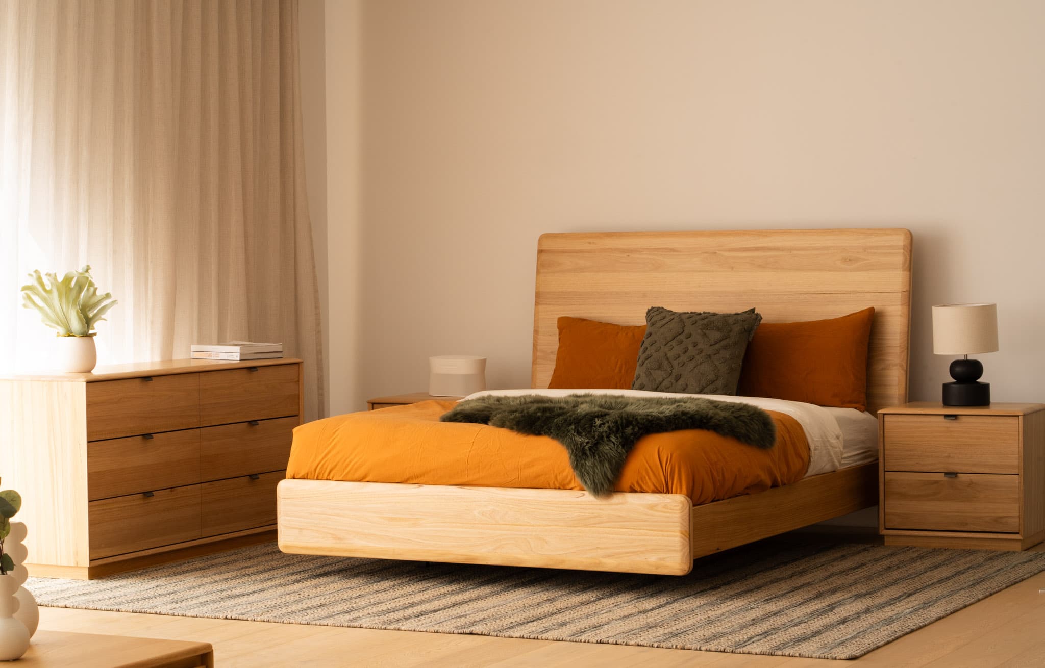 Warm bedroom with a timber bed, orange linen and matching bedside tables.