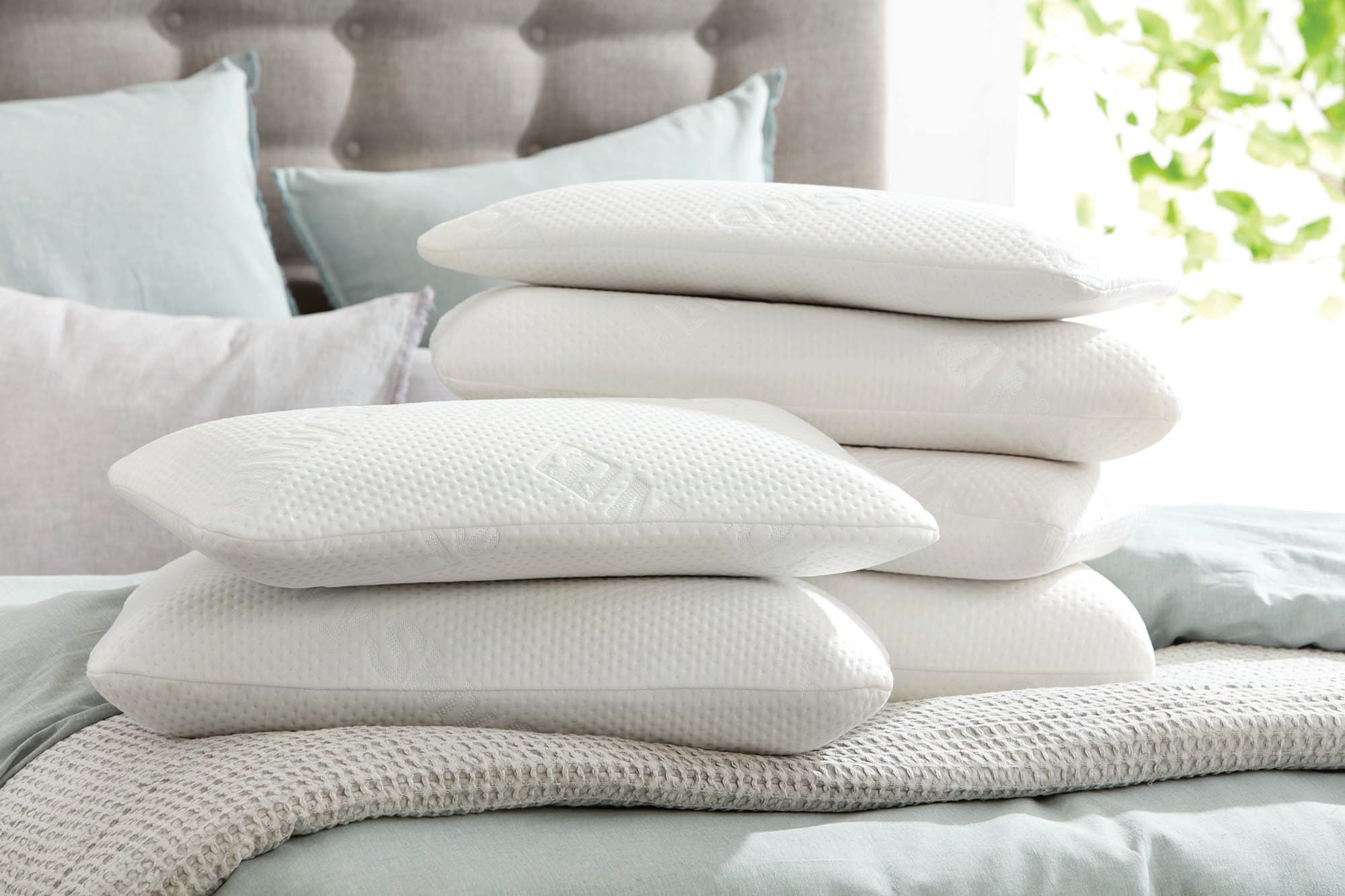 Stack of pillows in different heights on a bed.