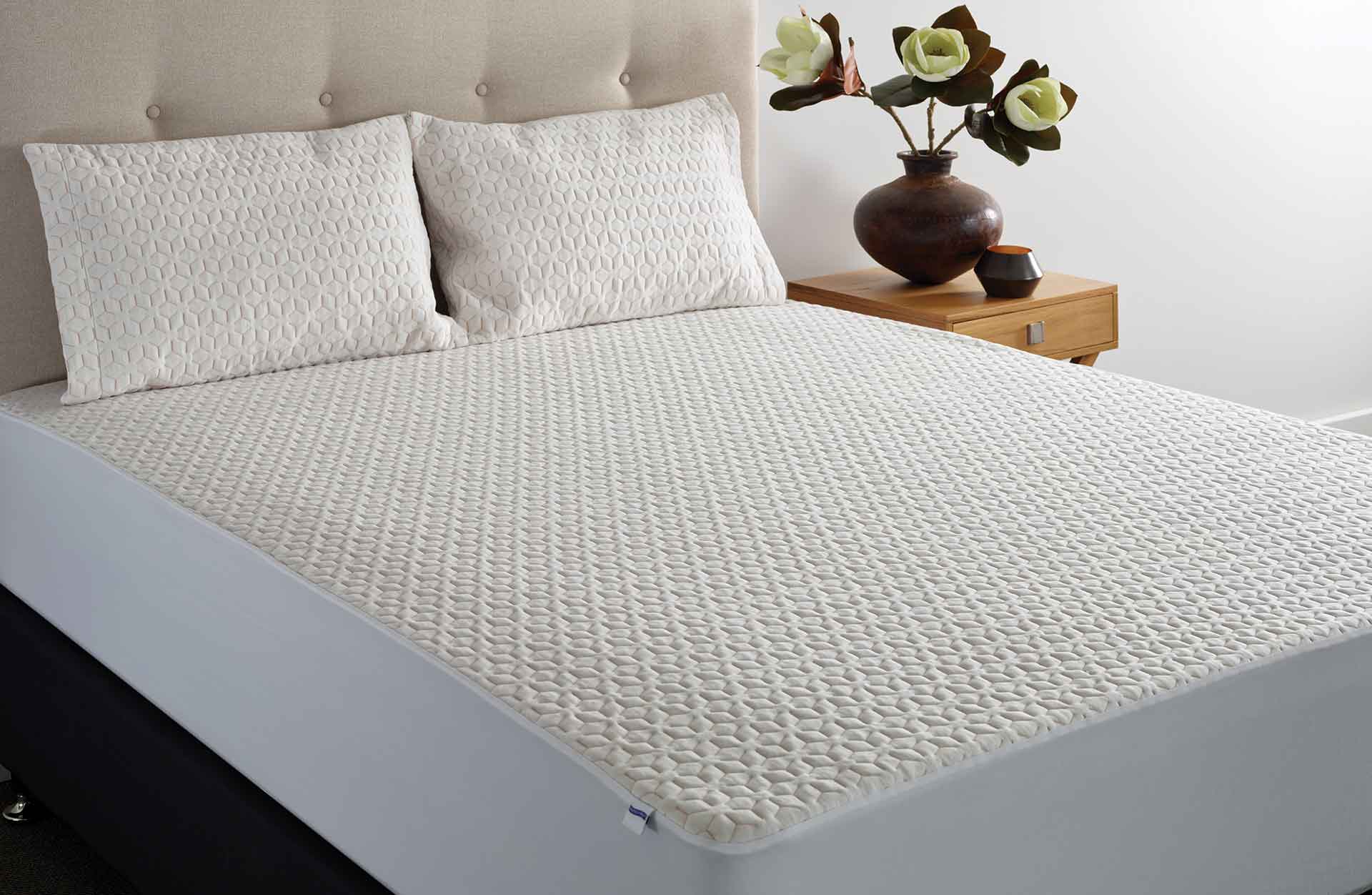 Quilted mattress protector fitted over a mattress.