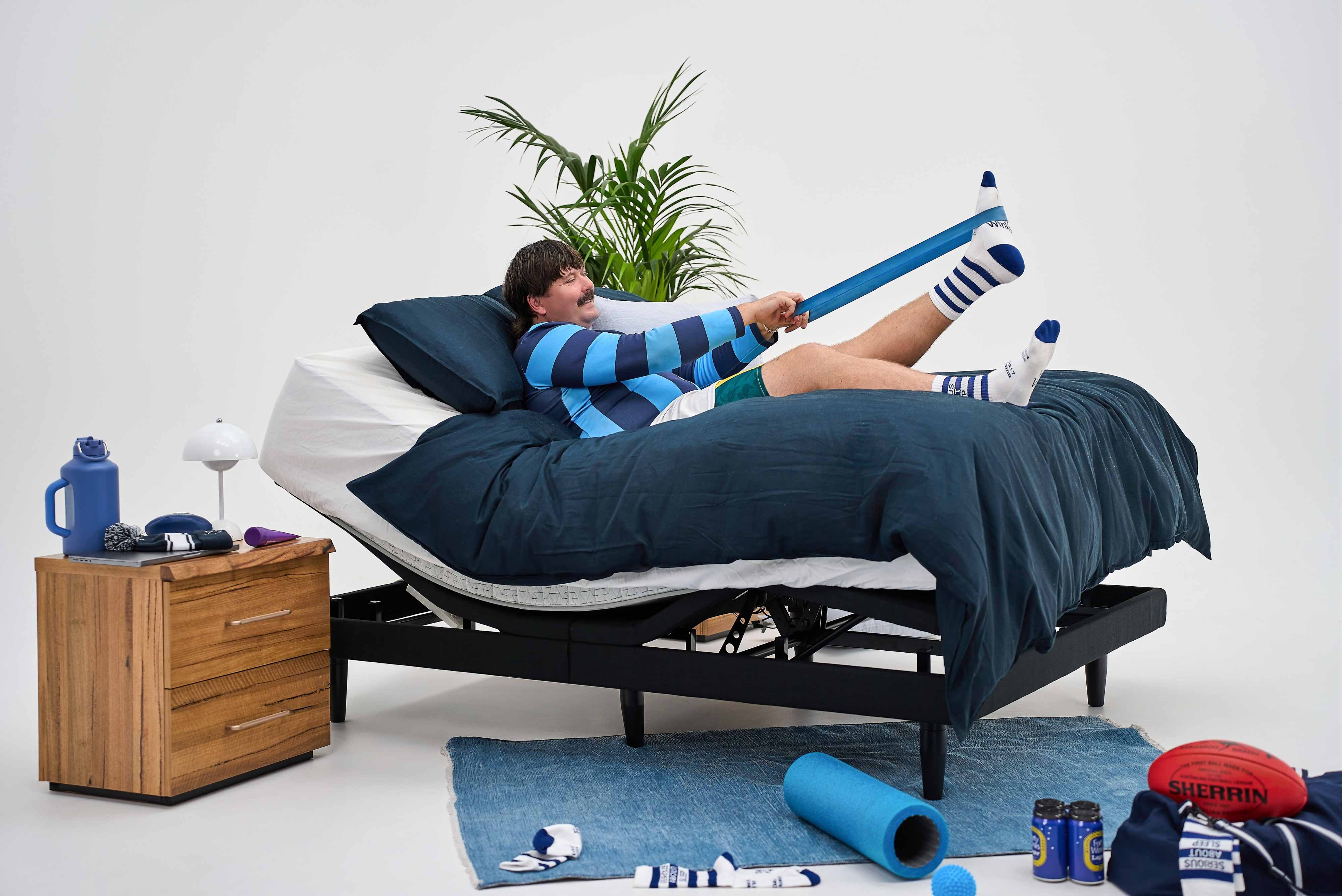 Man in football socks stretching on a raised adjustable bed.