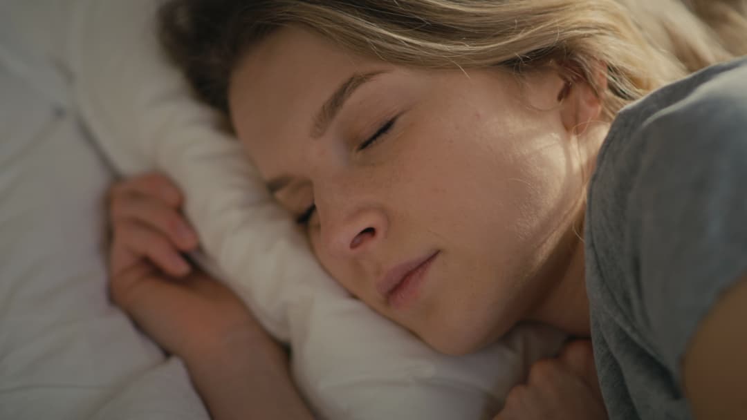 Close-up of a woman sleeping peacefully on a white pillow