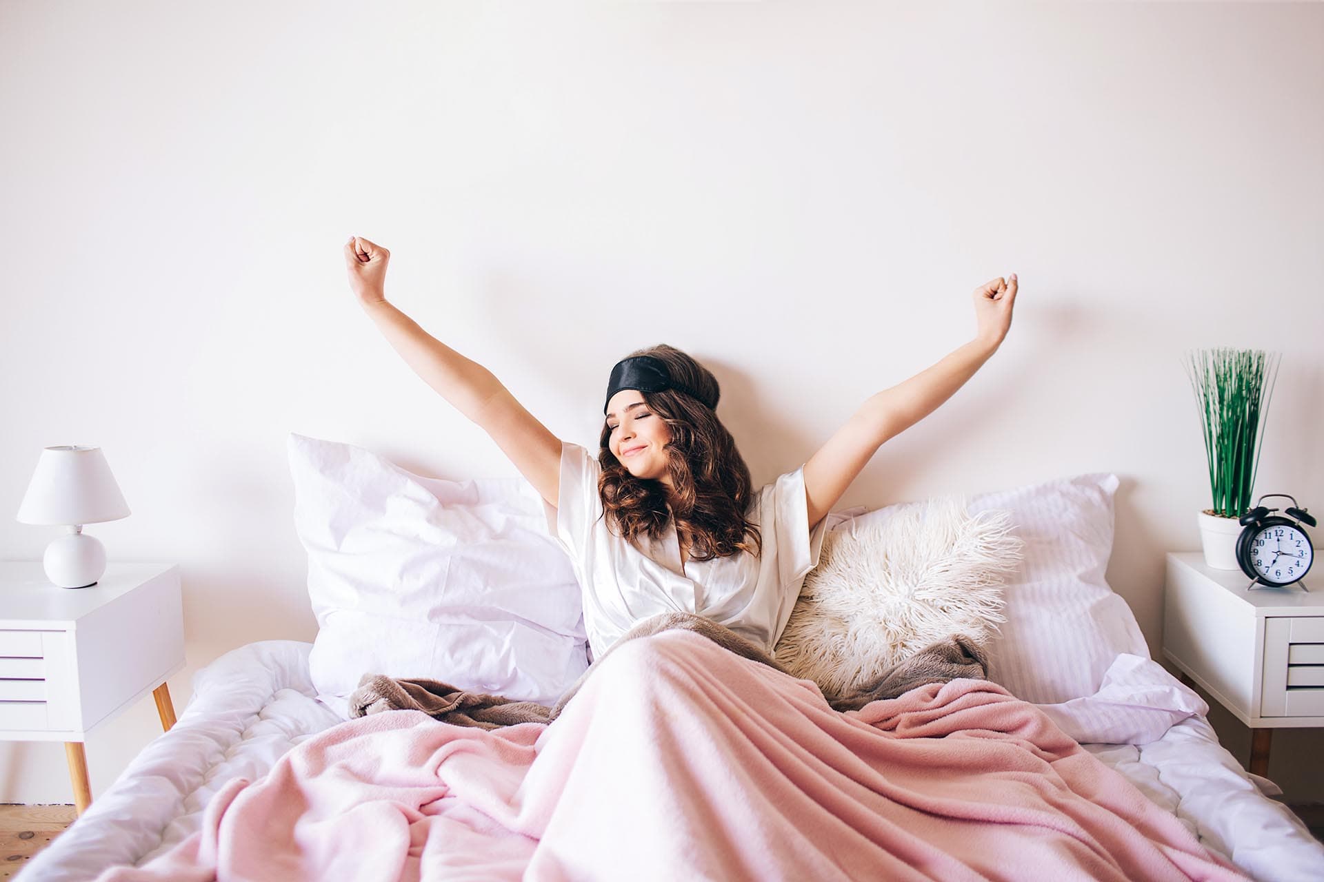 Woman stretching happily as she wakes up in bed.