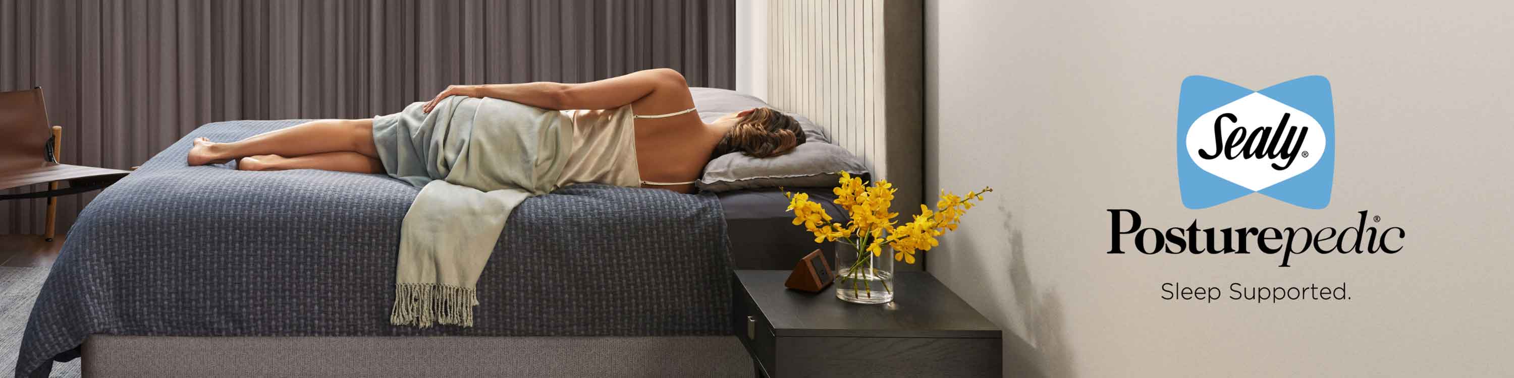 Woman sleeping on her side on a made bed. Sealy Posturepedic. Sleep Supported.